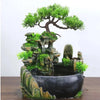 A resin desktop fountain featuring a mossy rock landscape and a miniature green tree.