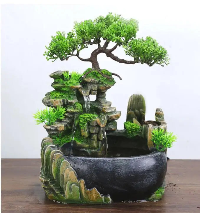 A resin desktop fountain featuring a mossy rock landscape and a miniature green tree.