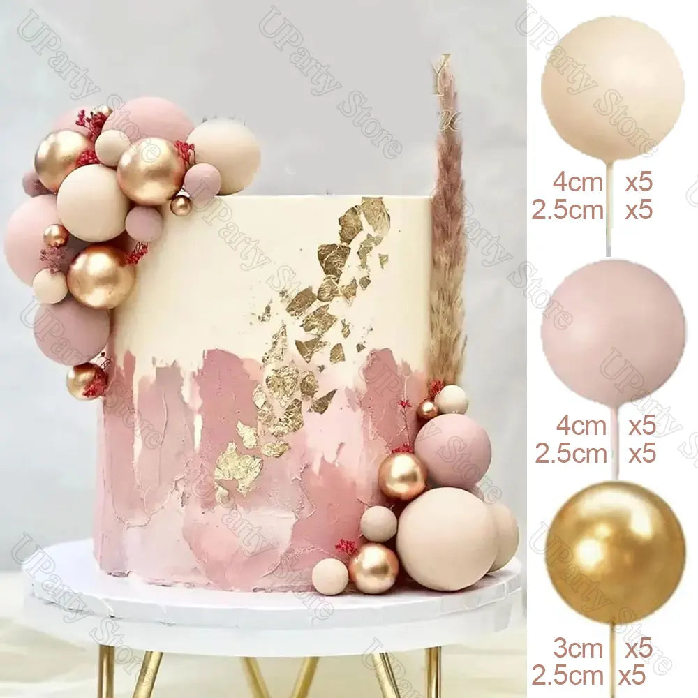 A tiered cake decorated with pink and gold watercolor paint splatters and round ball decorations.