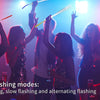 A group of people celebrating with fiber optic LED glow wands in various flashing modes under bright lights.