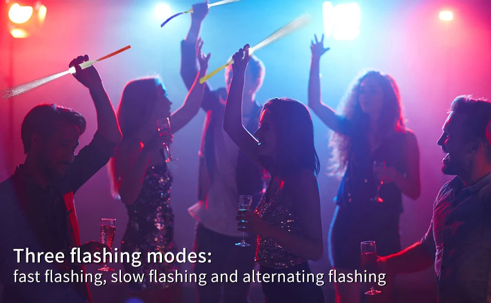A group of people celebrating with fiber optic LED glow wands in various flashing modes under bright lights.