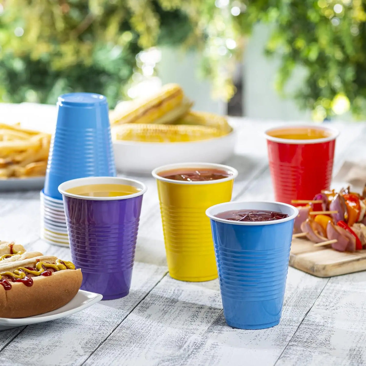 A collection of colorful disposable party cups in various shades of blue, purple, and yellow are displayed on a white surface