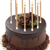 A dark chocolate birthday cake decorated with metallic gold candles and holders.