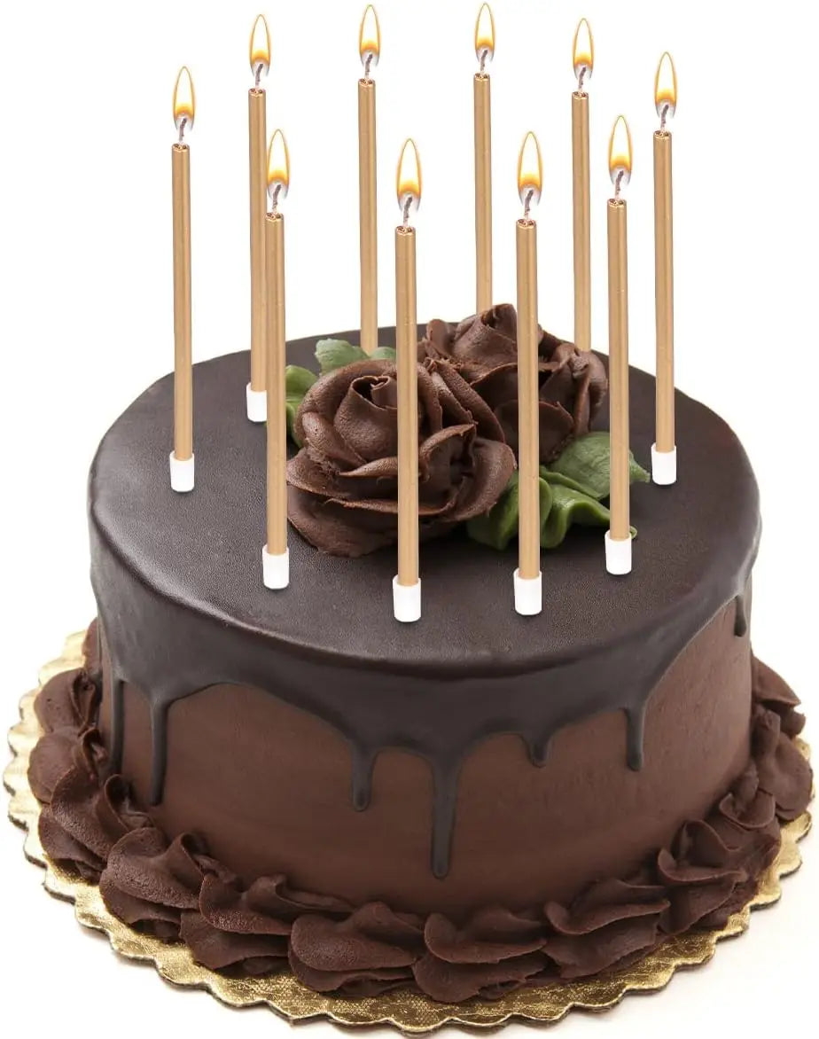 A dark chocolate birthday cake decorated with metallic gold candles and holders.