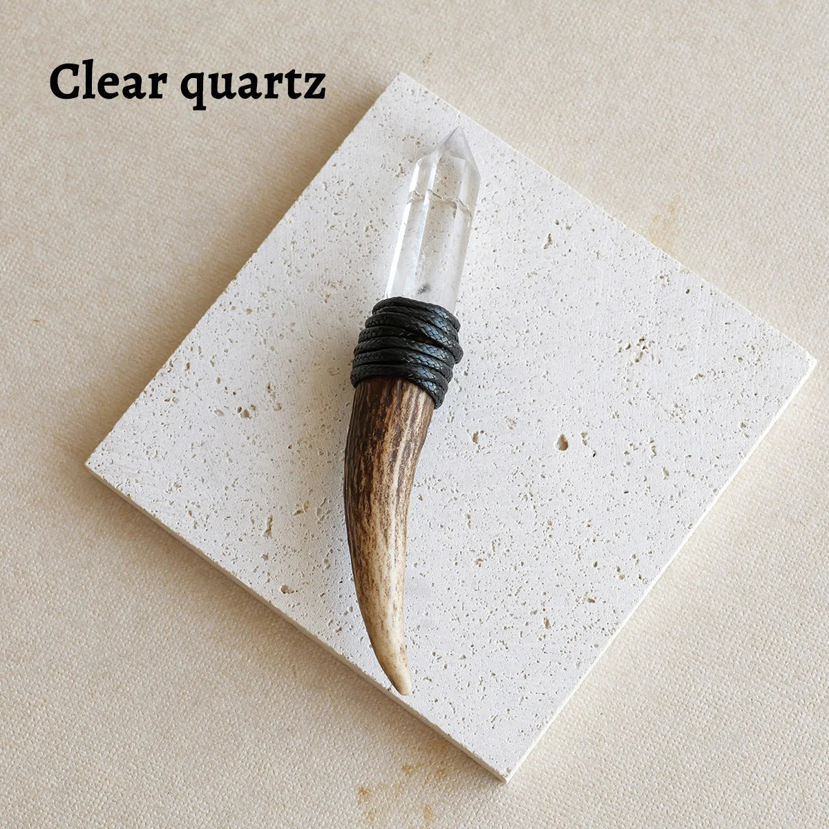 A clear quartz scepter wand with a wooden handle and black cord wrapped around it, displayed on a white square card.