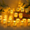 A collection of glowing yellow LED tea light candles in decorative paper lampshades arranged on a wooden surface.