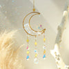 Handcrafted moon crystal suncatcher with a gold crescent and prism pendant hanging from a branch.