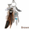 A brown bohemian dream catcher keychain featuring a feather, silver beads, and tassels.