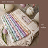 A collection of pink and green scented soy blend candles in long sticks displayed on a lace fabric with white pearls.