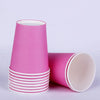 A stack of pink disposable tableware cups and a single cup lying on its side.