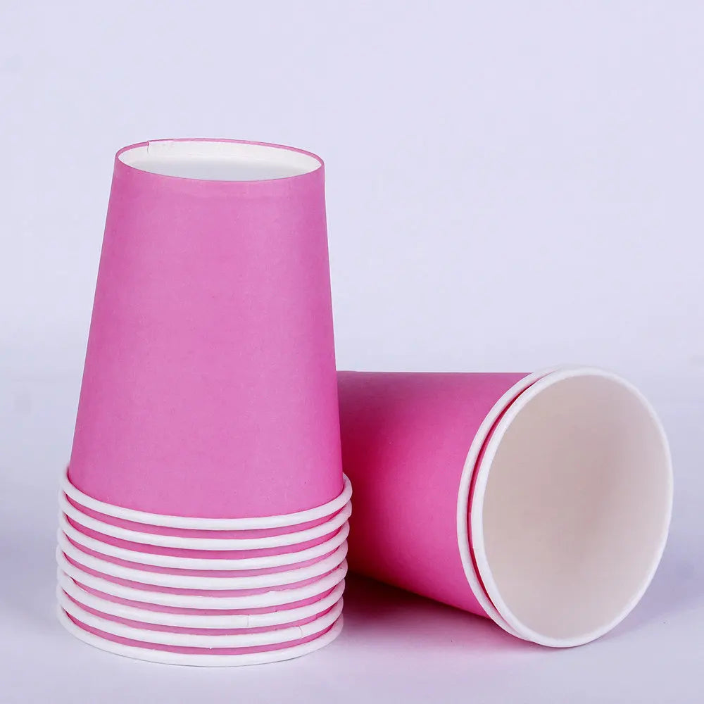 A stack of pink disposable tableware cups and a single cup lying on its side.