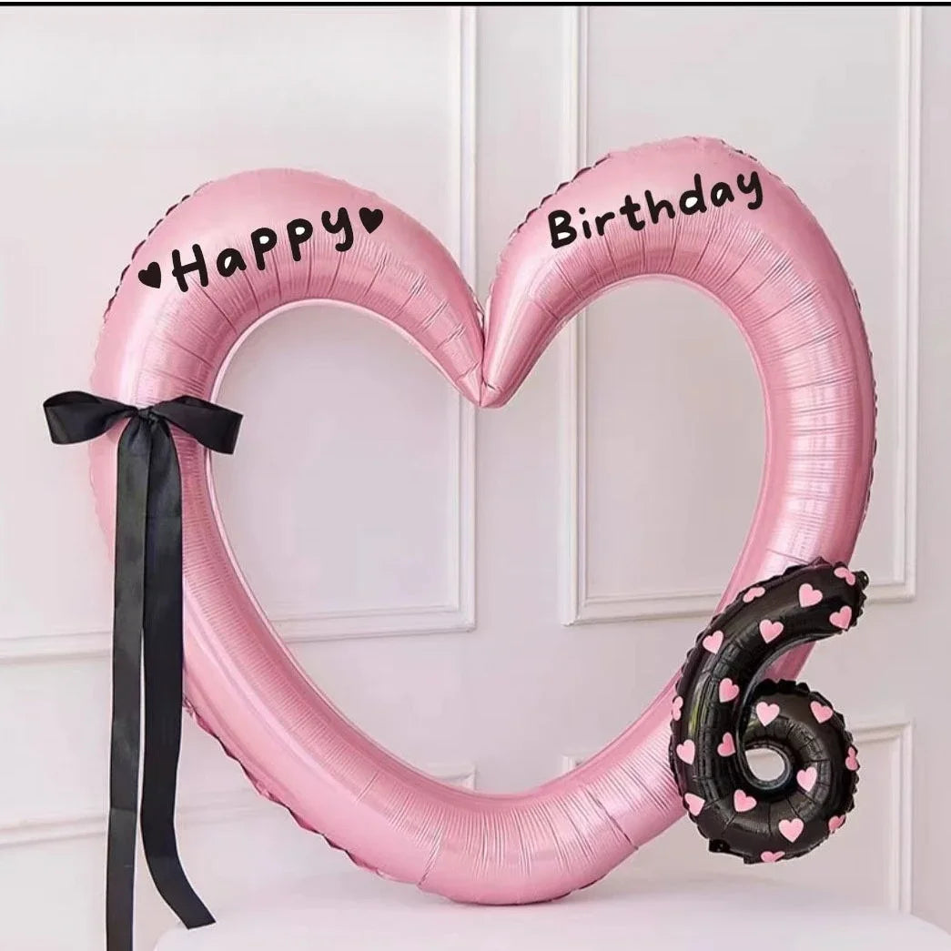 Pink heart-shaped balloon decoration with Happy Birthday text and a black six on a white background