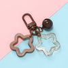 A brown pendant charm with a heart shape and a clear star shape attached to a keyring.
