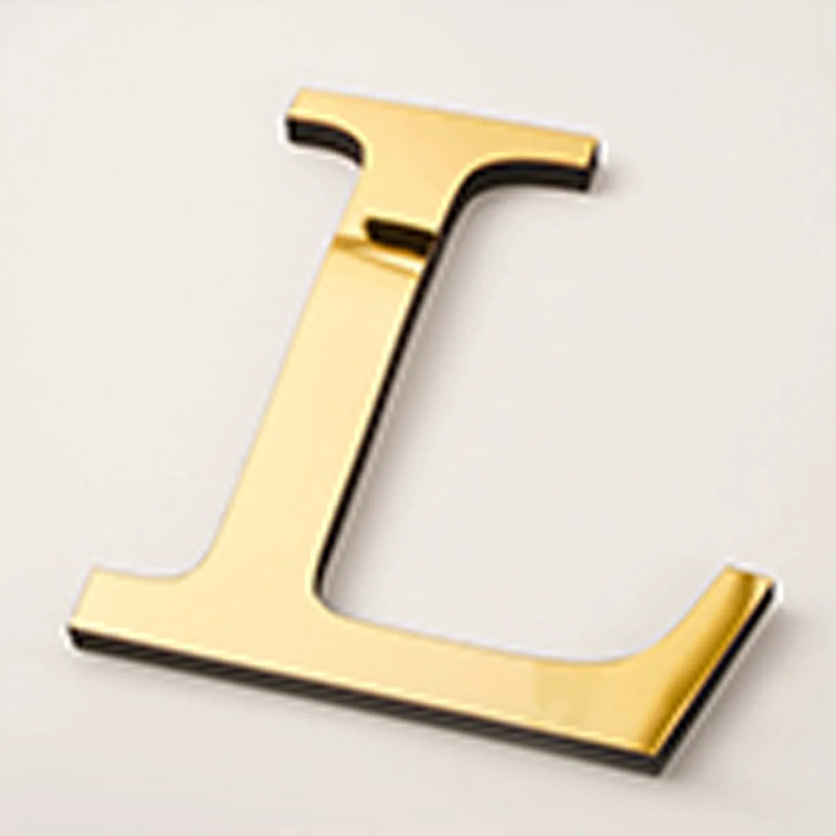 A gold acrylic mirror letter L wall sticker, 20cm in size.