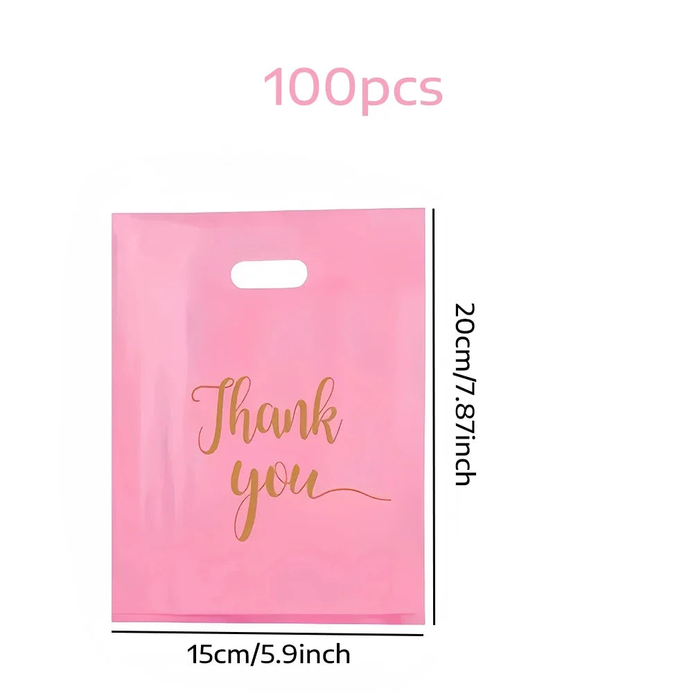 A pack of 100 pink clear plastic thank you gift bags with gold script writing