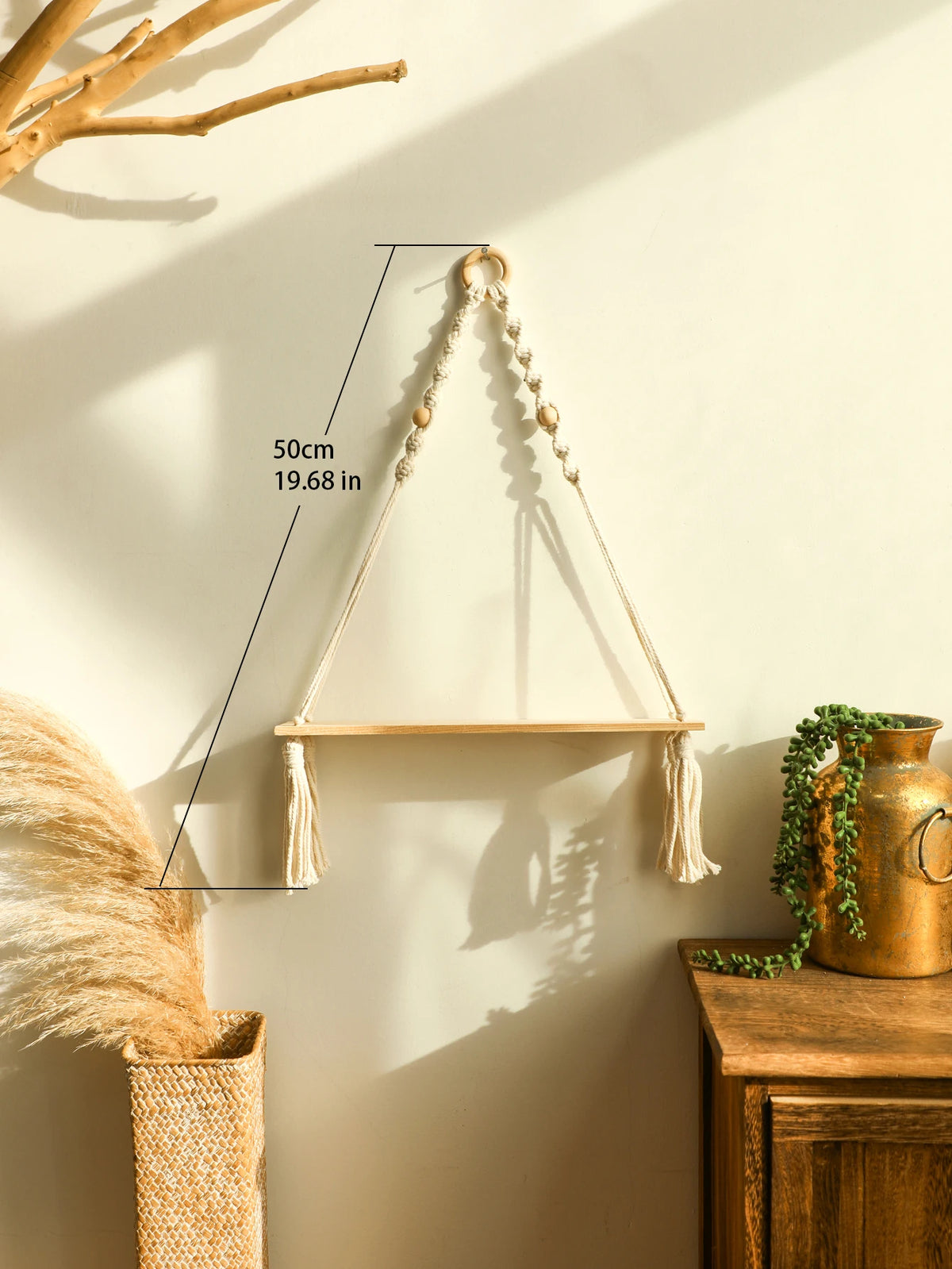 A macrame wood floating wall shelf with a hanging rope is displayed against a light wall, casting a shadow.