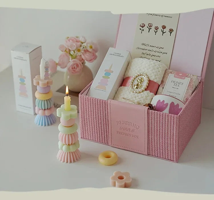 A pink box contains a candle, a gold ring, and floral elements for aromatherapy candles.
