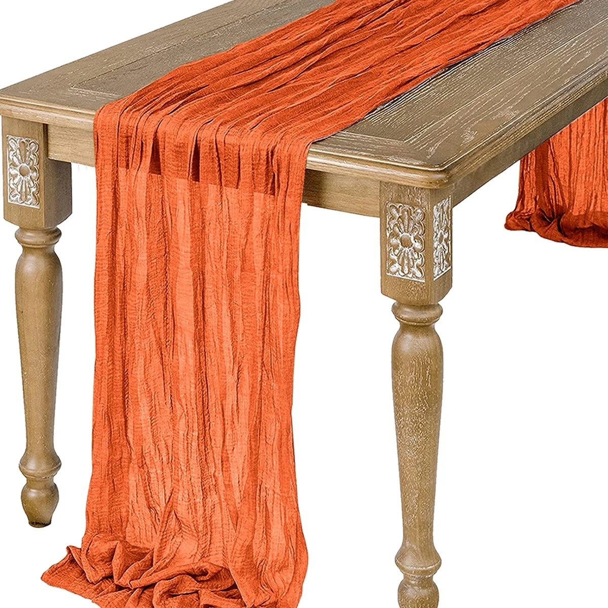 Orange semi-sheer gauze table runner draped over a wooden table.