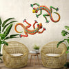 Handcrafted metal gecko wall art featuring colorful lizards displayed above two wicker chairs.