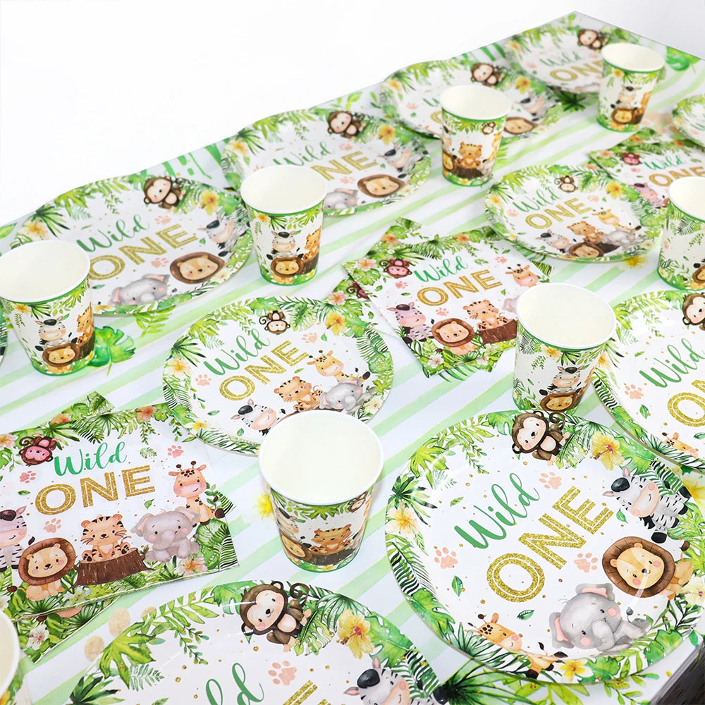 A green and white tableware set for a Wild One birthday party featuring animal prints like lions, elephants, and monkeys.