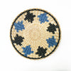 Round woven straw wall decor featuring black and blue geometric patterns.