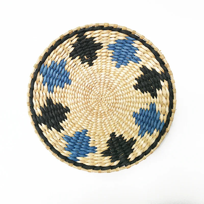 Round woven straw wall decor featuring black and blue geometric patterns.