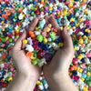 Hands holding a handful of assorted colorful resin miniature figurines for DIY decor