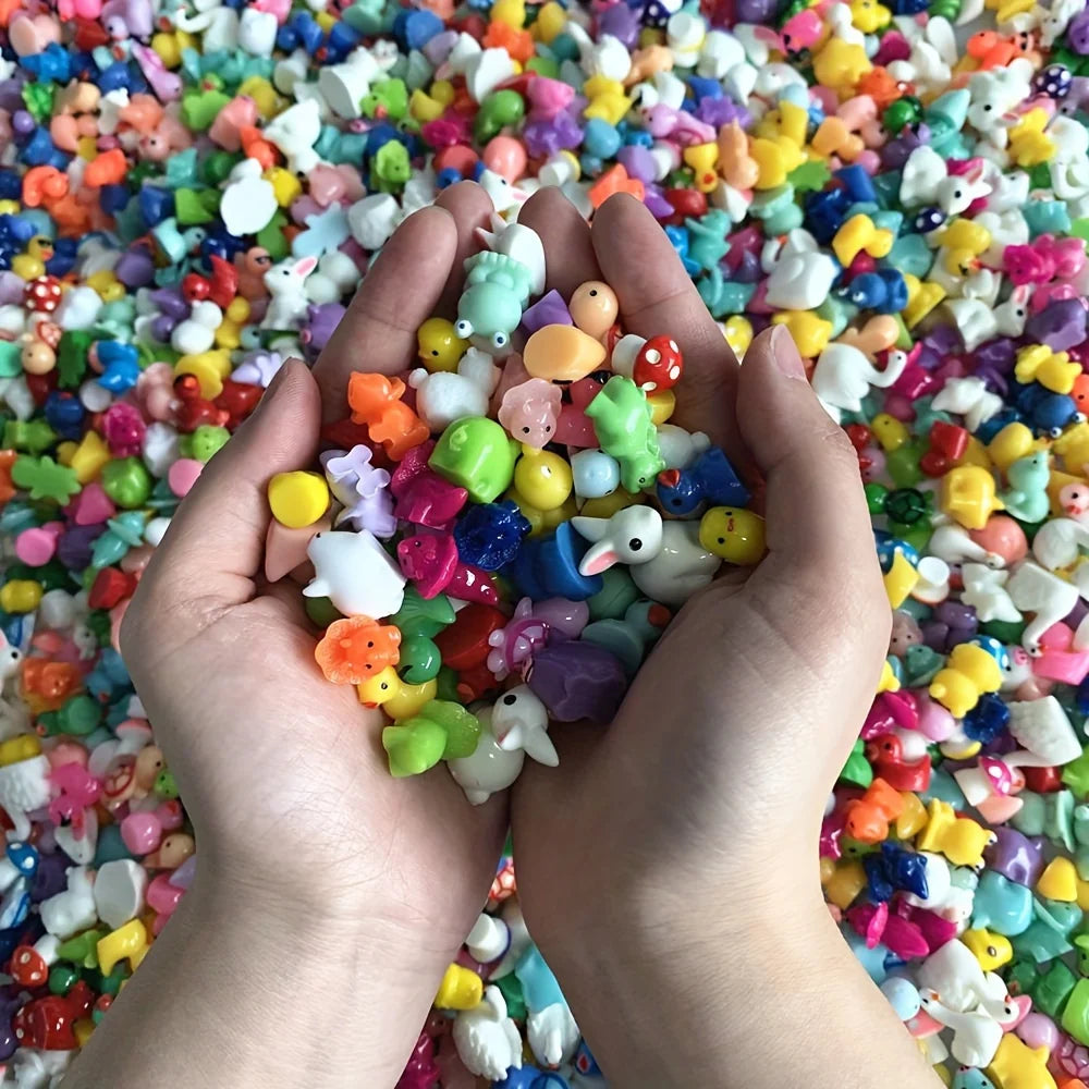 Hands holding a handful of assorted colorful resin miniature figurines for DIY decor