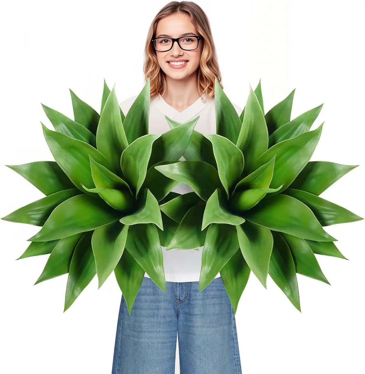 A woman holds a vibrant green artificial agave plant indoors.