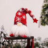 A red and white knitted gnome decoration with a white beard and red star on a metal stand.