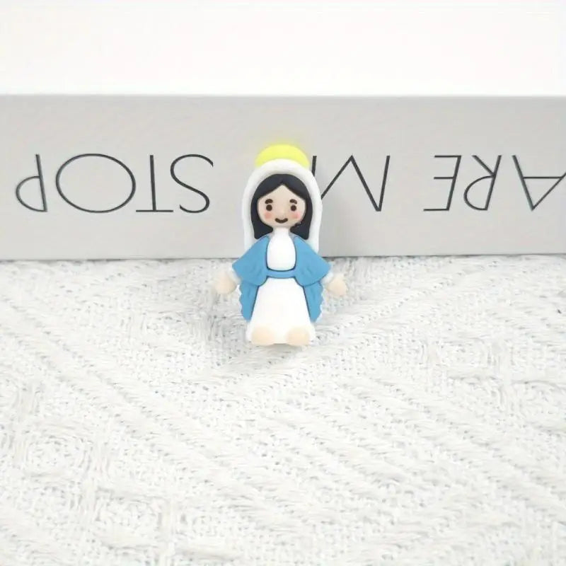 A small resin statue of the Virgin Mary with a yellow halo and blue and white robes.
