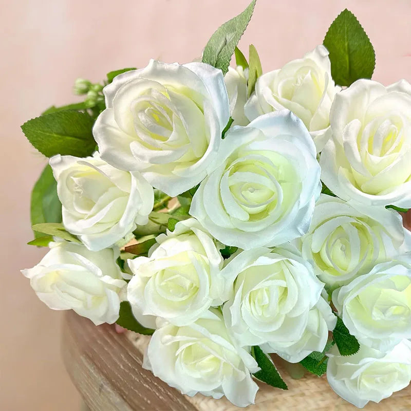 A bouquet of white and pale green artificial silk roses arranged in a natural setting.