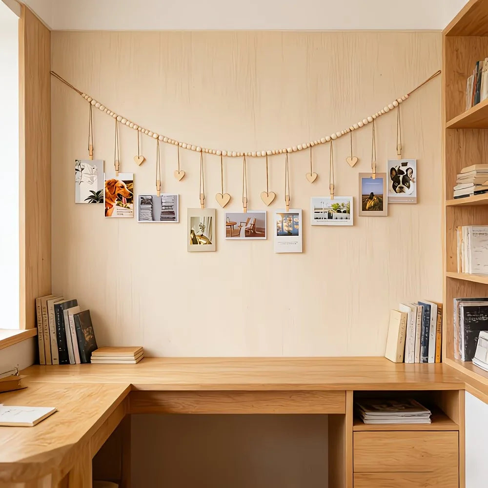 A wooden shelf display featuring a beaded photo garland hanging on the wall above a light wood desk.