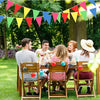 A family enjoying an outdoor picnic under a colorful pennant banner in a green park.