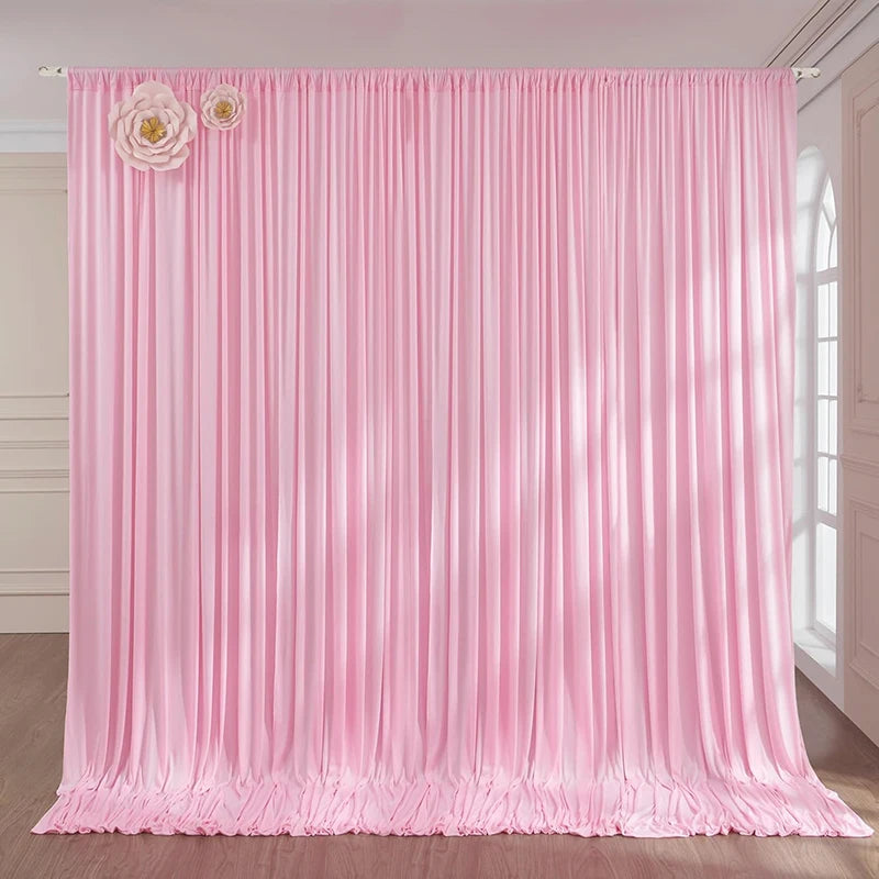 Pink pleated fabric backdrop curtain with floral accents used as a studio or event drape