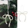 A set of elegant pearl bow Christmas tree ornaments with white string and red accents.