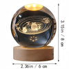 A spherical glass decoration featuring a solar system engraved on its surface.