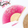 Pink folding fan with color-changing fabric and cherry blossom designs against a white background.