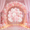 An archway decorated with pink and white balloons and sheer fabric, set up for an event.