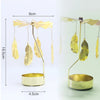 Gold rotating candle holder with feather-like arms and a circular base for tealights