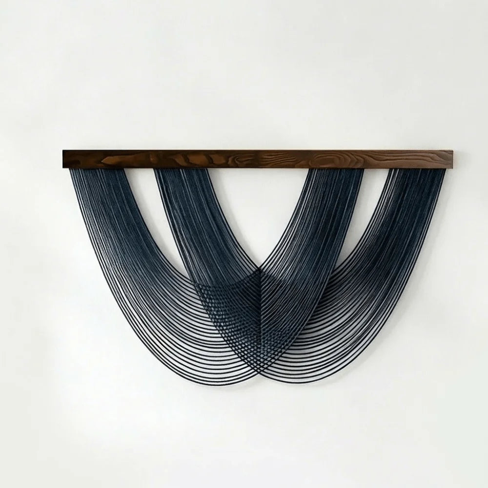 A dark blue macrame wall tapestry featuring three curved fringe elements suspended from a wooden bar.