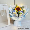 A bouquet of handmade crochet flowers featuring a large yellow sunflower and blue accent flowers, wrapped in light blue paper