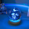 A crystal ball night light featuring a glowing blue jellyfish and a moon against a dark background.