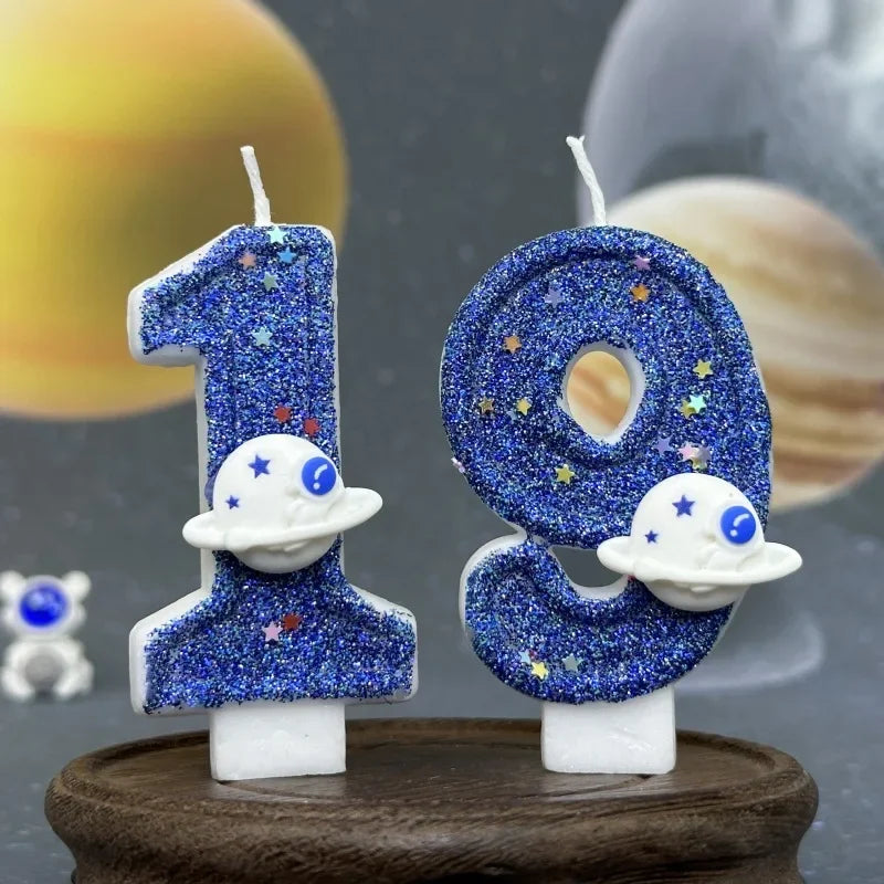 Two birthday candles shaped like the numbers 1 and 0, decorated with blue glitter and white planet designs.