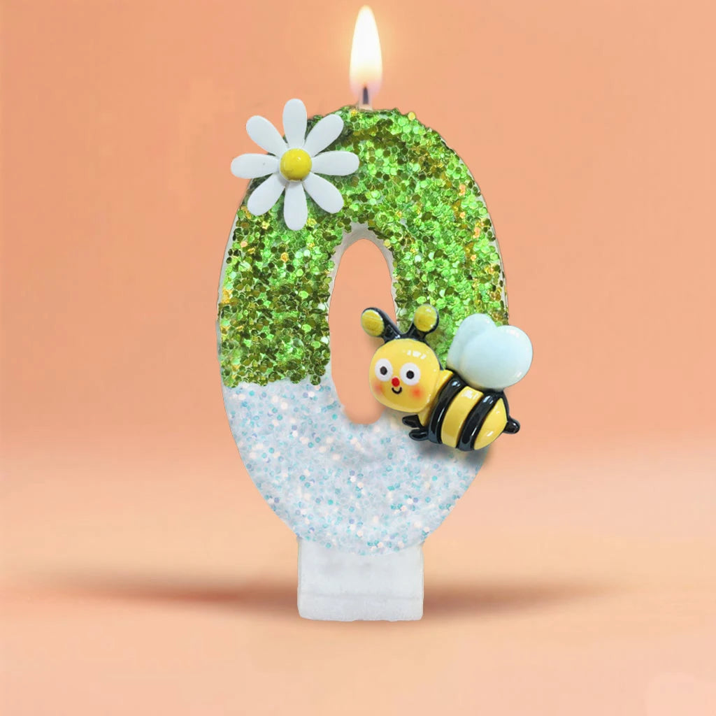 A large number zero decorated with green glitter, a white flower, and a bee figurine, set against a soft orange background.