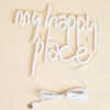 A white LED neon sign shaped like the words my happy place, featuring a USB power cord.