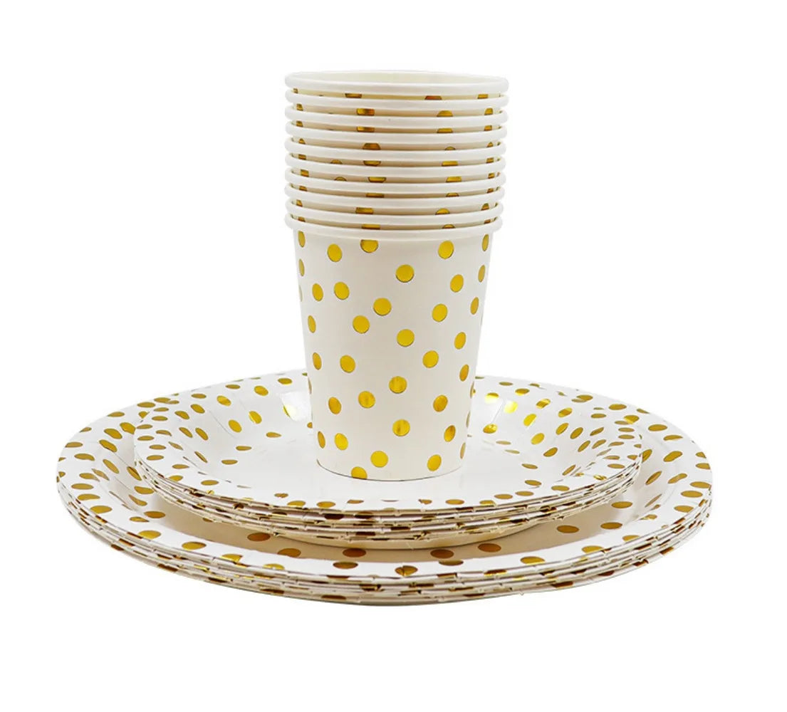 A stack of white disposable cups and a plate set with gold polka dots on a white background.