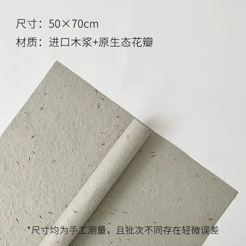 A sheet of light green decorative packaging paper with scattered dried flower petals rolled up.