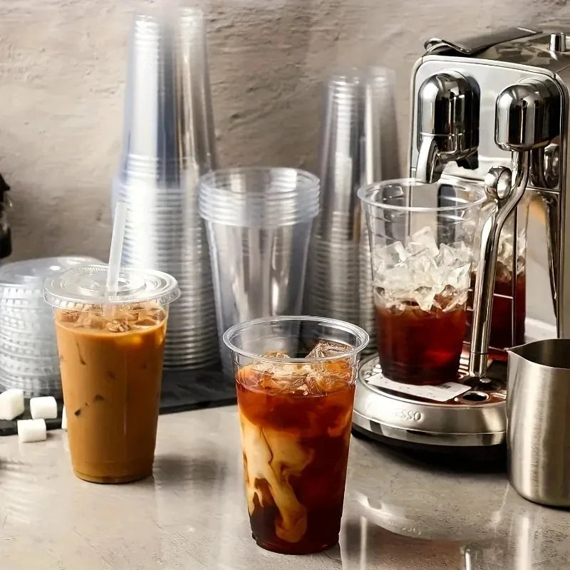 A close-up of several iced coffee drinks in clear plastic cups and a metal coffee dispenser.