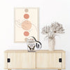 A framed artwork featuring a hand silhouette and circular shapes, displayed next to a heart-shaped acrylic decoration.